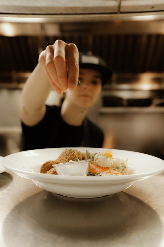 A culinary team member sprinkles parsley on a dish in The Renfrew Pub